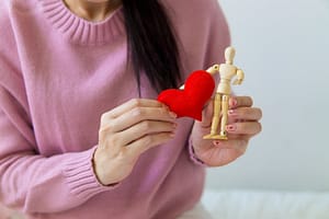 crop woman with handmade heart and wooden figure